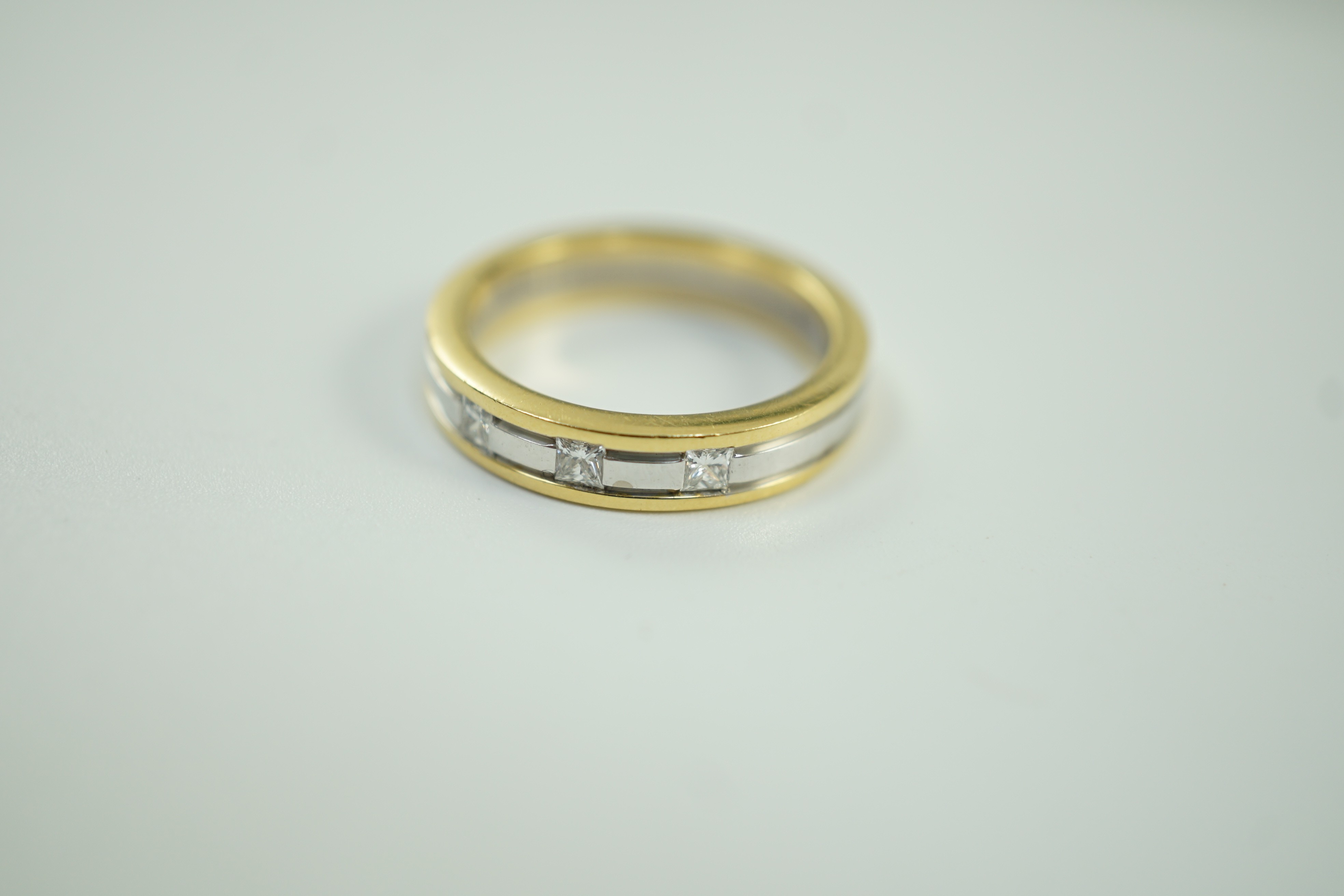 A modern Simbol two colour 18ct gold and gypsy set three stone diamond band, size M, gross weight 6.7 grams.